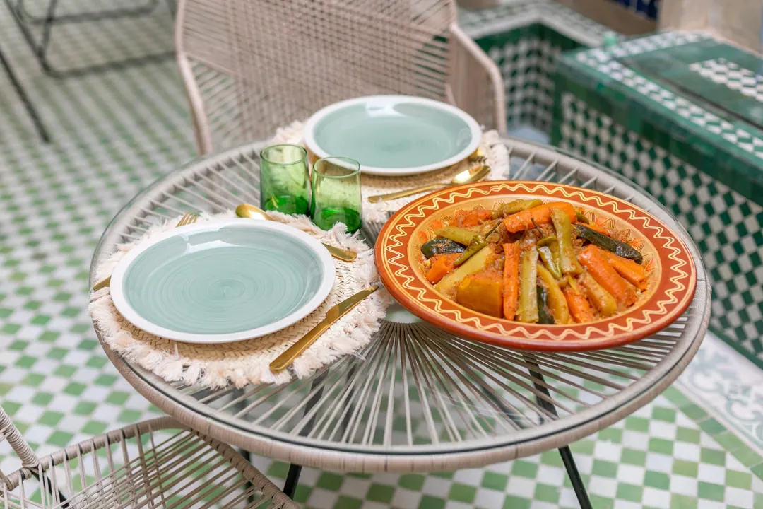 Seven-vegetable couscous in a terracotta dish with celadon plates