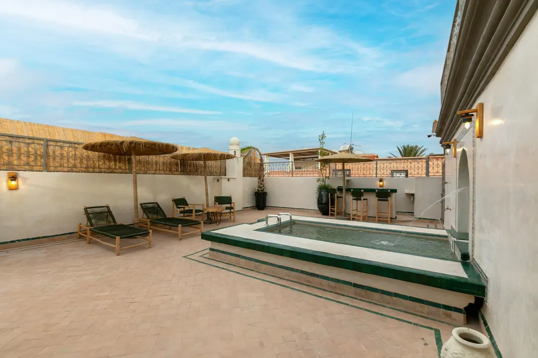 Rooftop terrace with a green-tiled plunge pool, wall fountain and reed parasols