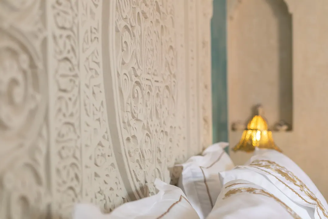 Turquoise room: carved plaster headboard against a deep turquoise wall, leather lounge chair
