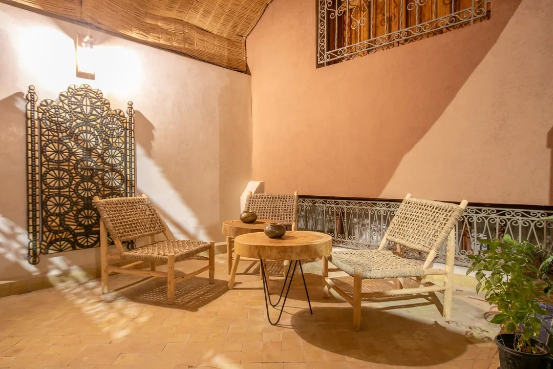 Shaded terrace with woven loungers and a carved wooden screen
