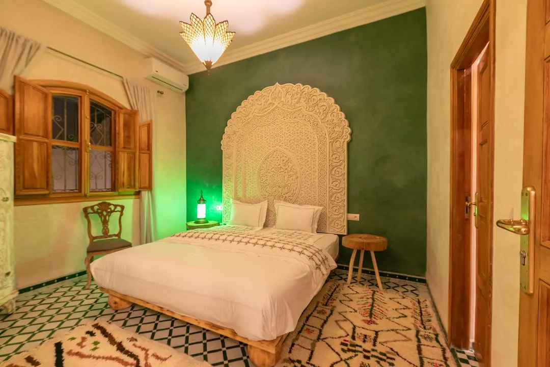 Emerald room: carved headboard on an emerald tadelakt wall, green lantern and zellige floor