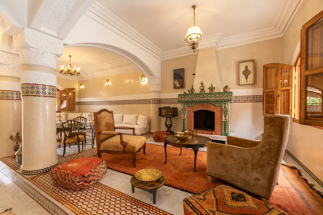 Grand salon with carved plaster arches, zellige columns, crystal chandeliers and Berber rugs