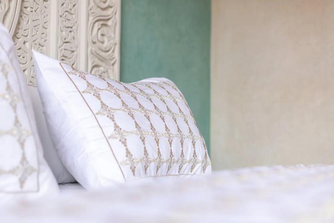 Embroidered linen pillows against a carved headboard