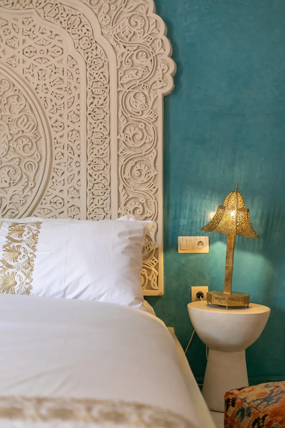 Turquoise room: carved plaster headboard against a deep turquoise wall, leather lounge chair