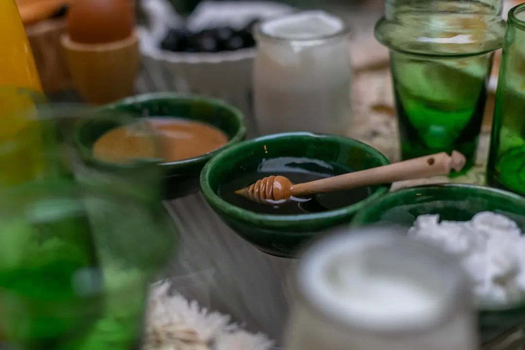 Detail of breakfast: green Beldi glasses, dates, cheese and fried eggs in a terracotta dish