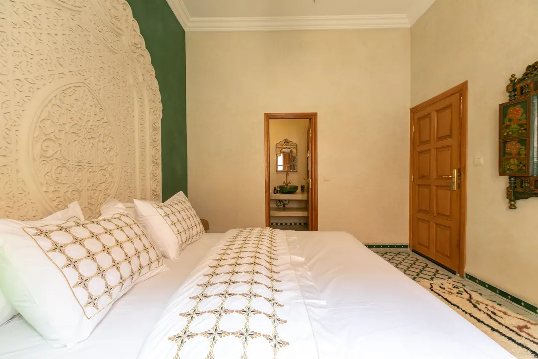 Emerald room: carved headboard on an emerald tadelakt wall, green lantern and zellige floor