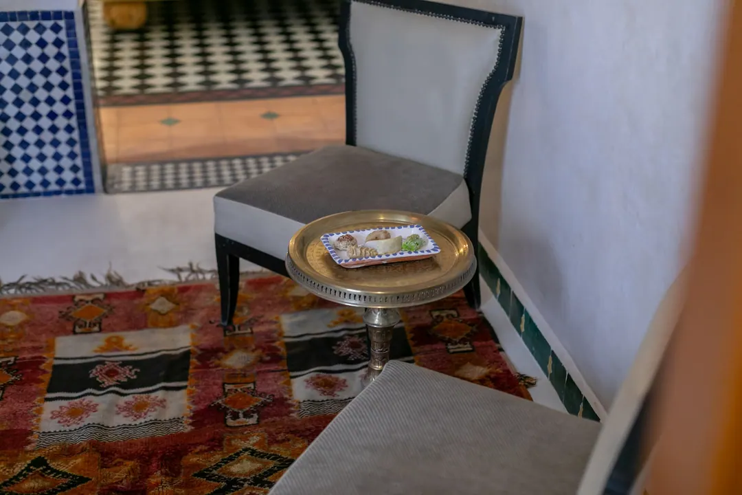 Ivory room: carved plaster headboard, bedside lamps and a black-and-white zellige floor