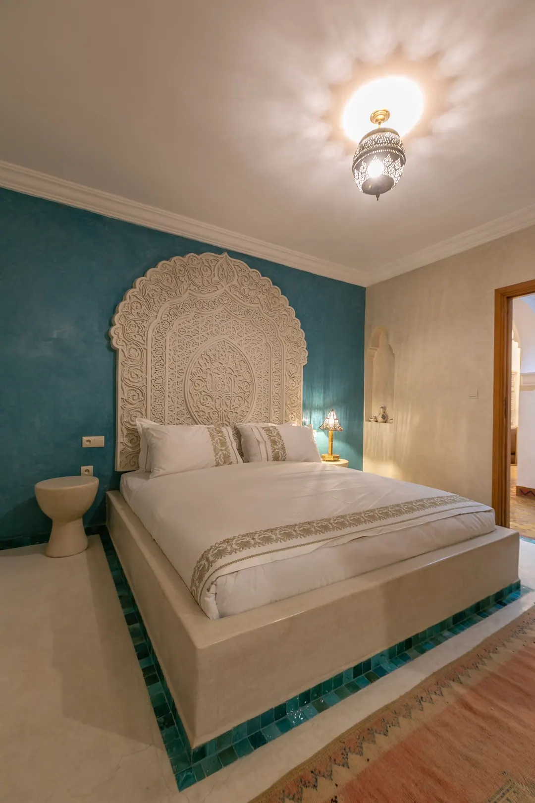 Turquoise room: carved plaster headboard against a deep turquoise wall, leather lounge chair