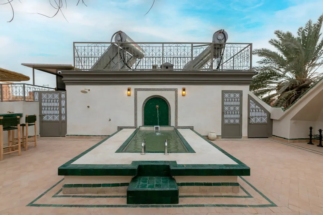 Rooftop terrace with a green-tiled plunge pool, wall fountain and reed parasols
