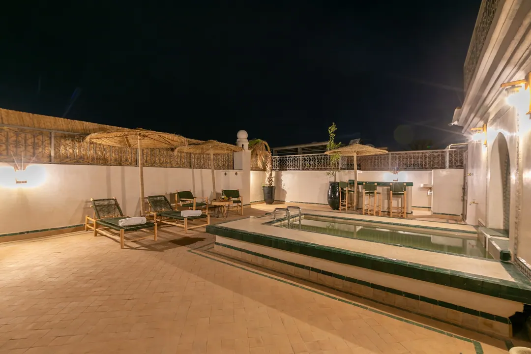 The rooftop plunge pool glowing under a night sky