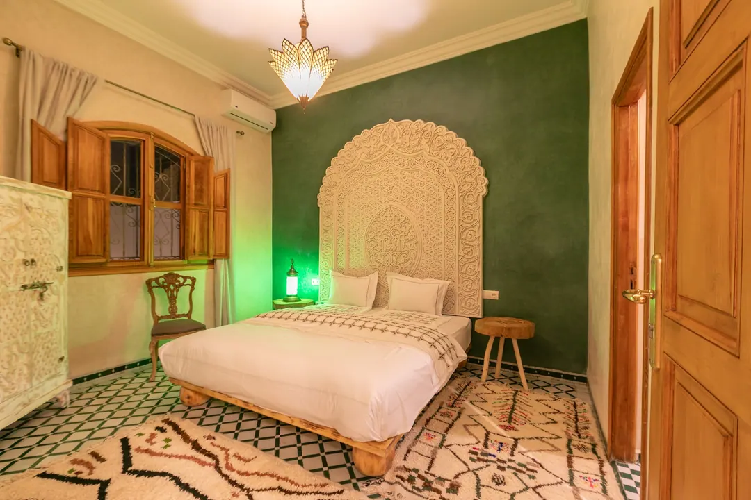 Emerald room: carved headboard on an emerald tadelakt wall, green lantern and zellige floor