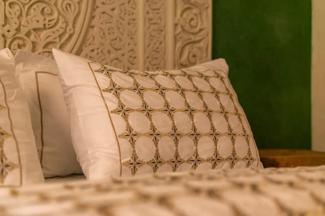 Embroidered linen pillows against a carved headboard