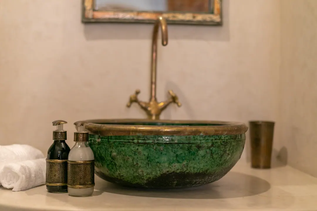Emerald room bathroom with a hand-glazed green basin and brass fittings