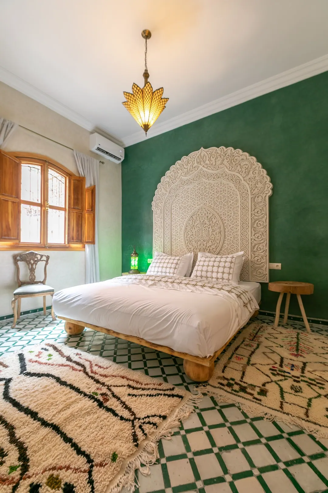 Emerald room: carved headboard on an emerald tadelakt wall, green lantern and zellige floor
