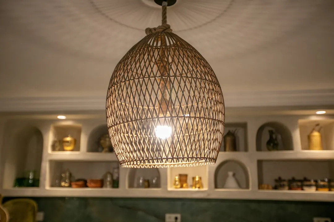 The riad kitchen with cedar cabinets, zellige splashback and woven pendant lights