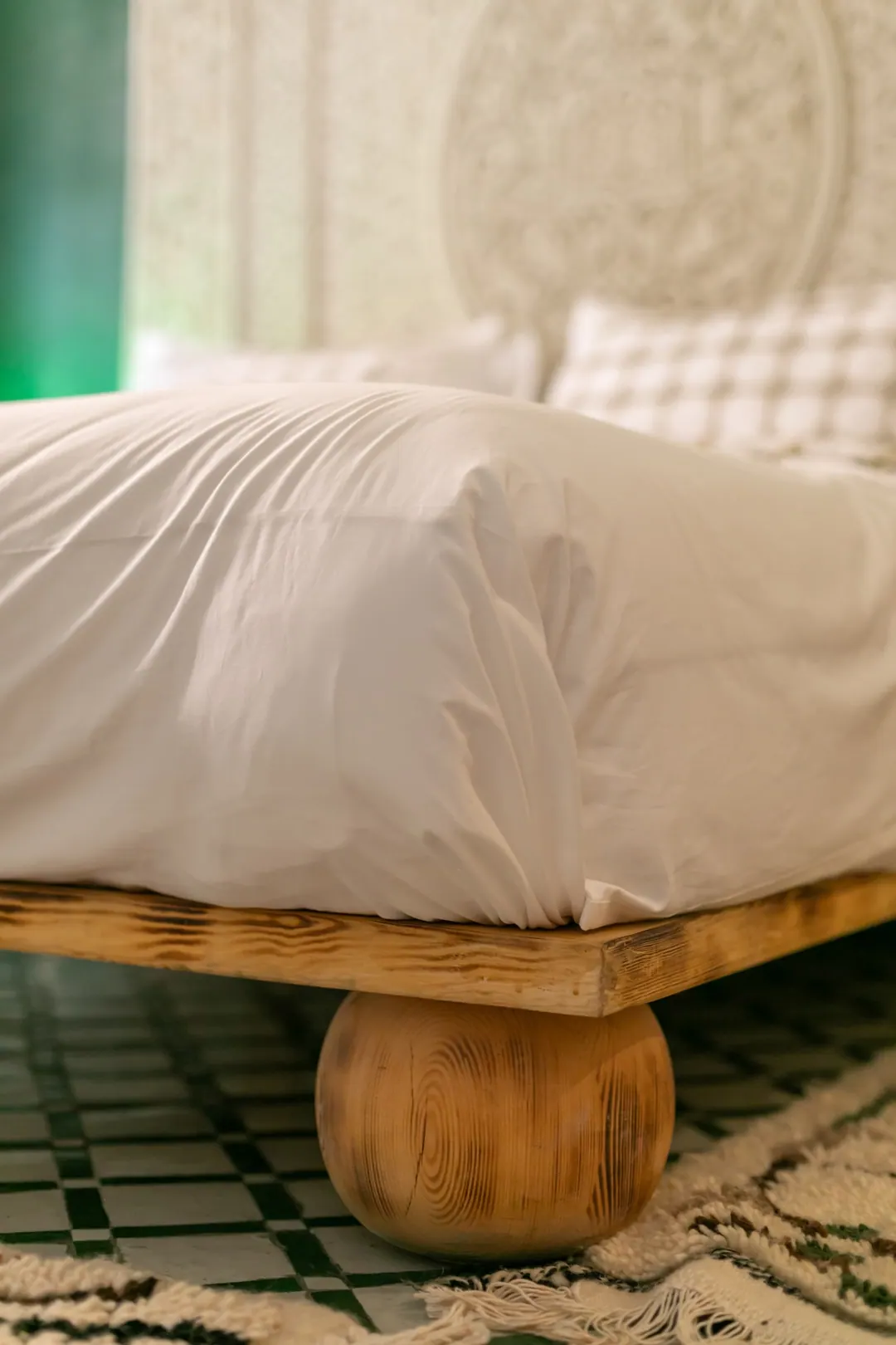 Emerald room: carved headboard on an emerald tadelakt wall, green lantern and zellige floor