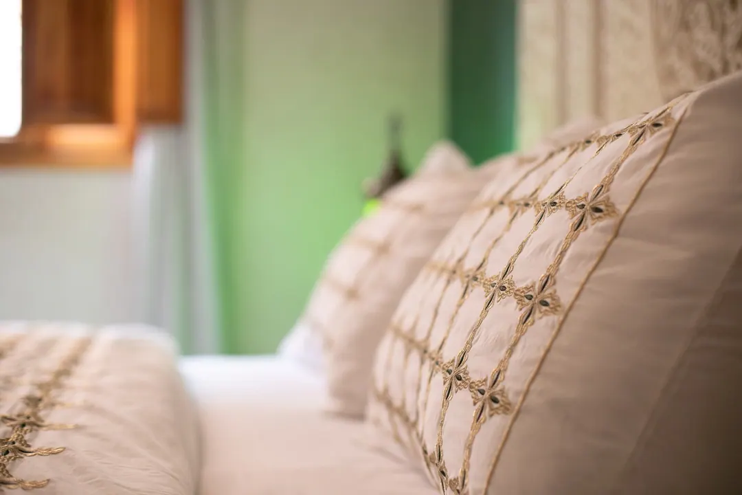 Emerald room: carved headboard on an emerald tadelakt wall, green lantern and zellige floor