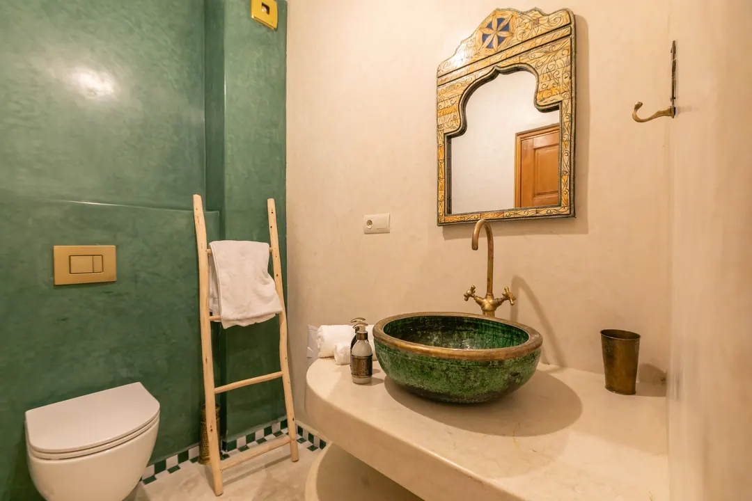 Emerald room bathroom with a hand-glazed green basin and brass fittings
