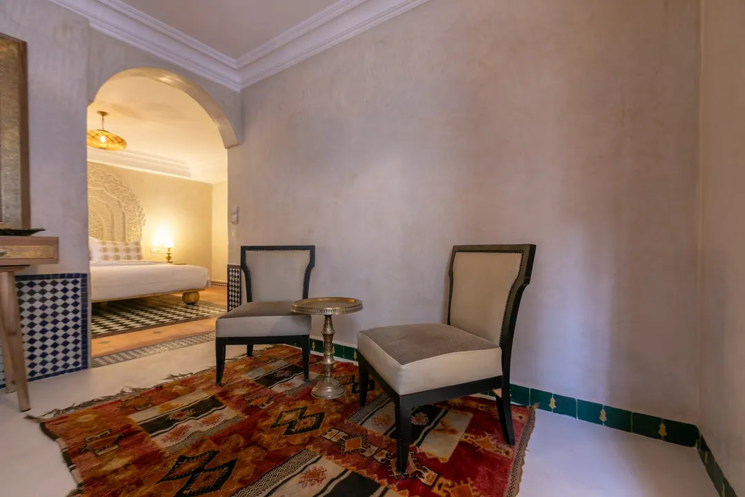 Ivory room: carved plaster headboard, bedside lamps and a black-and-white zellige floor