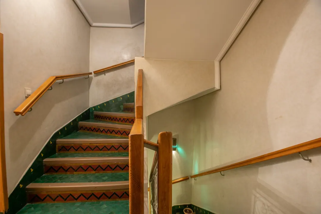 Staircase with green zellige steps and a cedar handrail