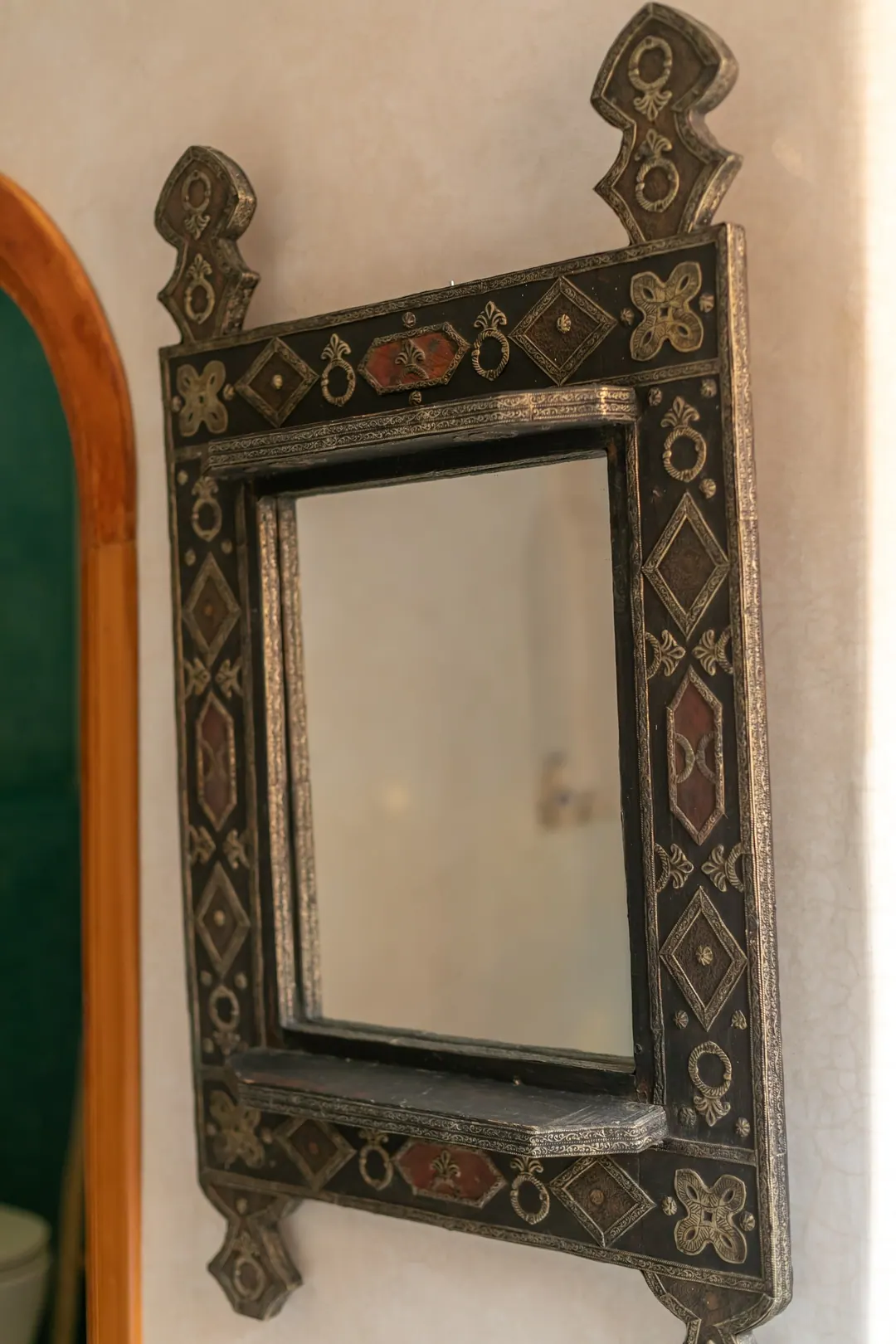 Turquoise room: carved plaster headboard against a deep turquoise wall, leather lounge chair