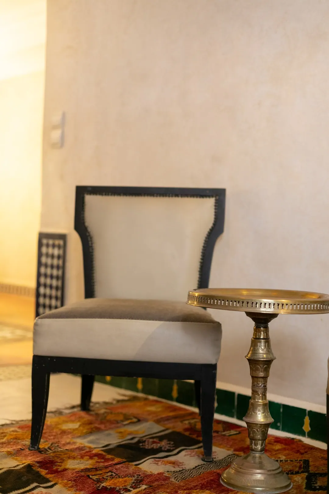 Ivory room: carved plaster headboard, bedside lamps and a black-and-white zellige floor