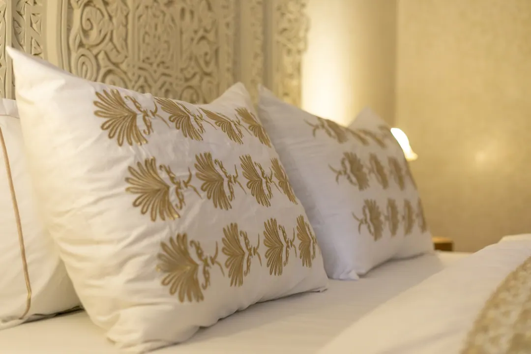 Embroidered linen pillows against a carved headboard