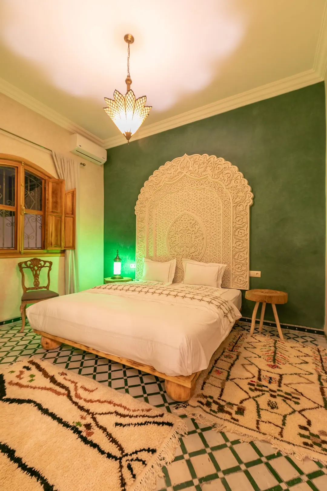 Emerald room: carved headboard on an emerald tadelakt wall, green lantern and zellige floor