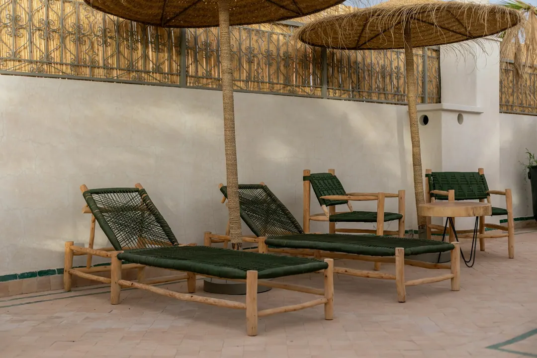 Cedar and green-cord sun loungers under reed parasols on the rooftop