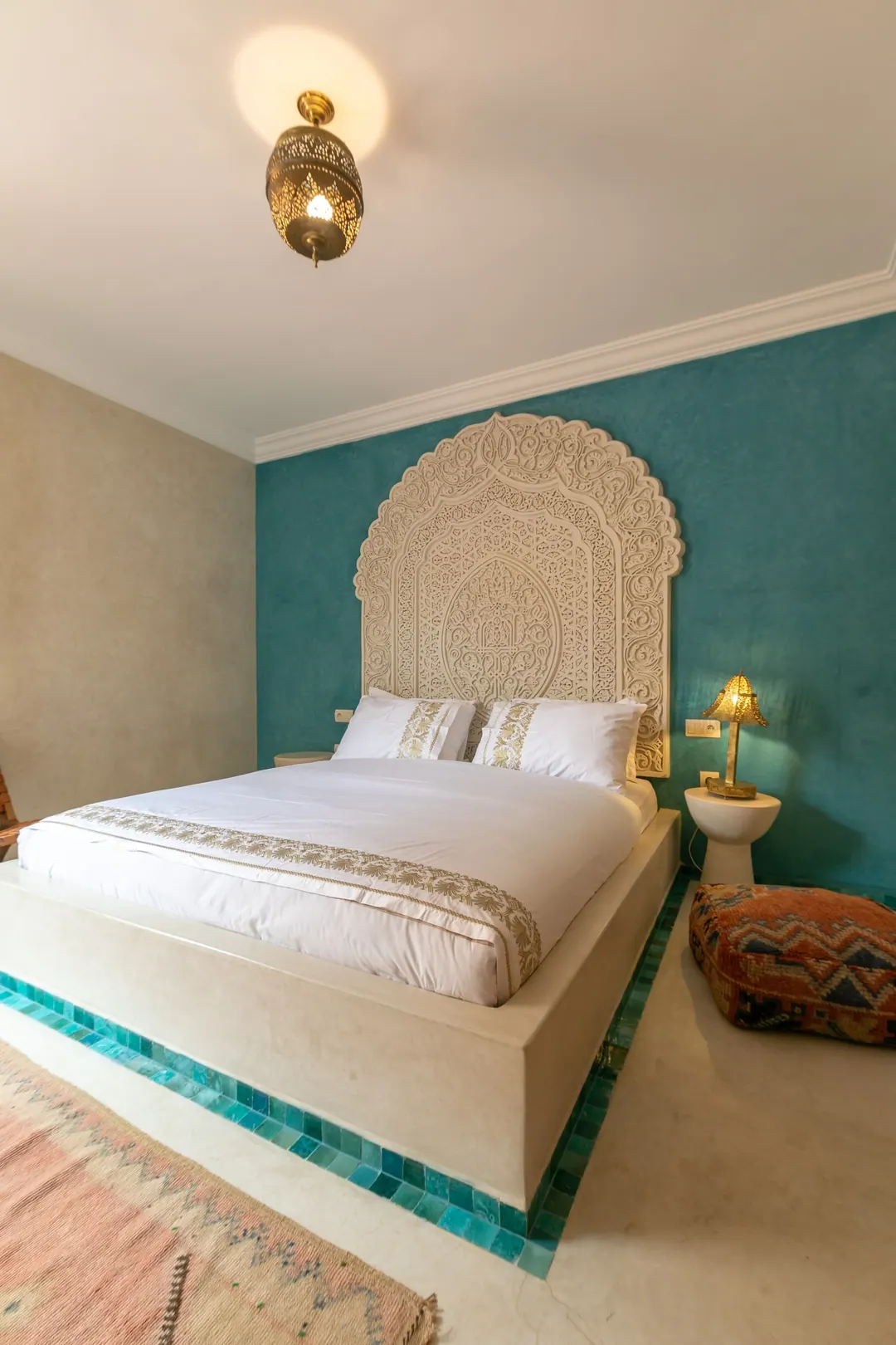 Turquoise room: carved plaster headboard against a deep turquoise wall, leather lounge chair