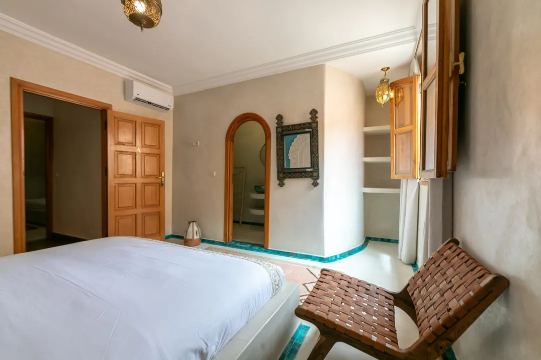 Turquoise room: carved plaster headboard against a deep turquoise wall, leather lounge chair