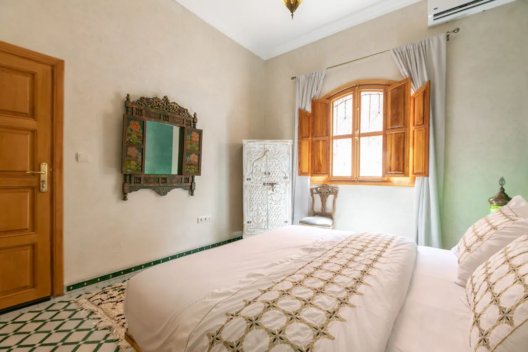 Emerald room: carved headboard on an emerald tadelakt wall, green lantern and zellige floor