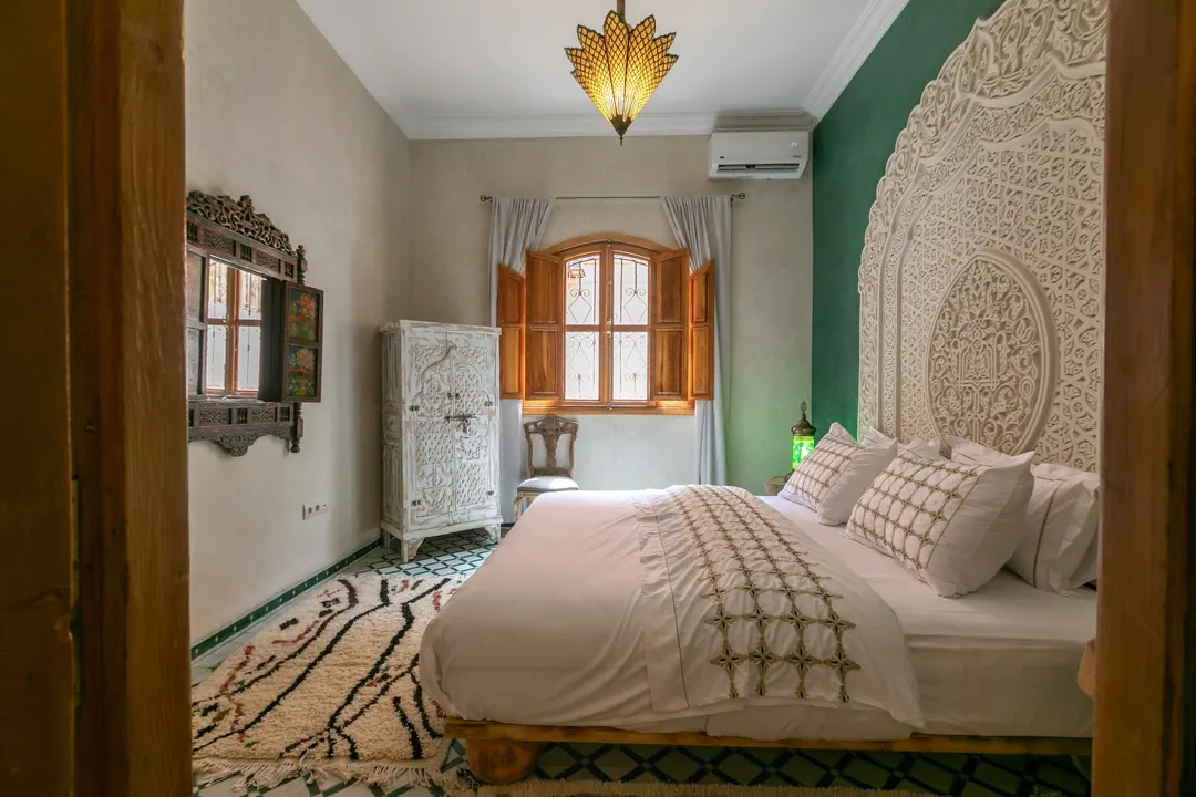 Emerald room: carved headboard on an emerald tadelakt wall, green lantern and zellige floor