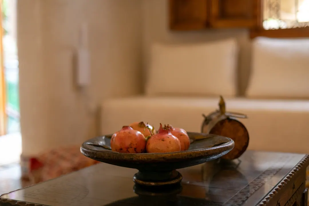 Ivory Moroccan sofa with a carved cedar table and a bowl of pomegranates