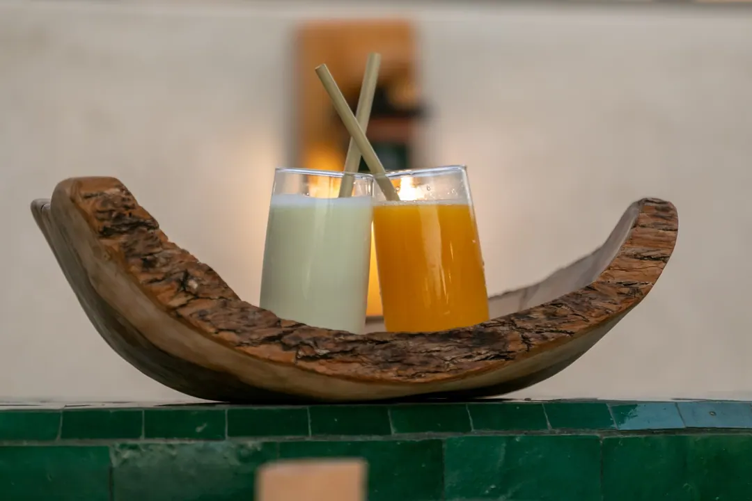 Fresh orange juice and almond milk in an olive-wood bowl by the pool
