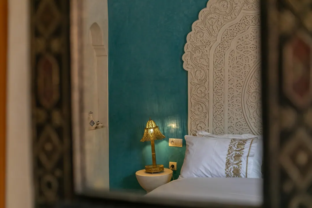 Turquoise room: carved plaster headboard against a deep turquoise wall, leather lounge chair