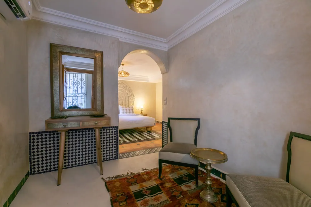 Ivory room: carved plaster headboard, bedside lamps and a black-and-white zellige floor