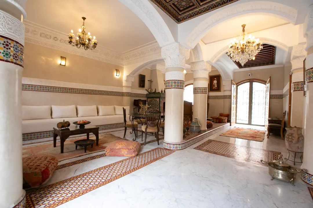 Grand salon with carved plaster arches, zellige columns, crystal chandeliers and Berber rugs