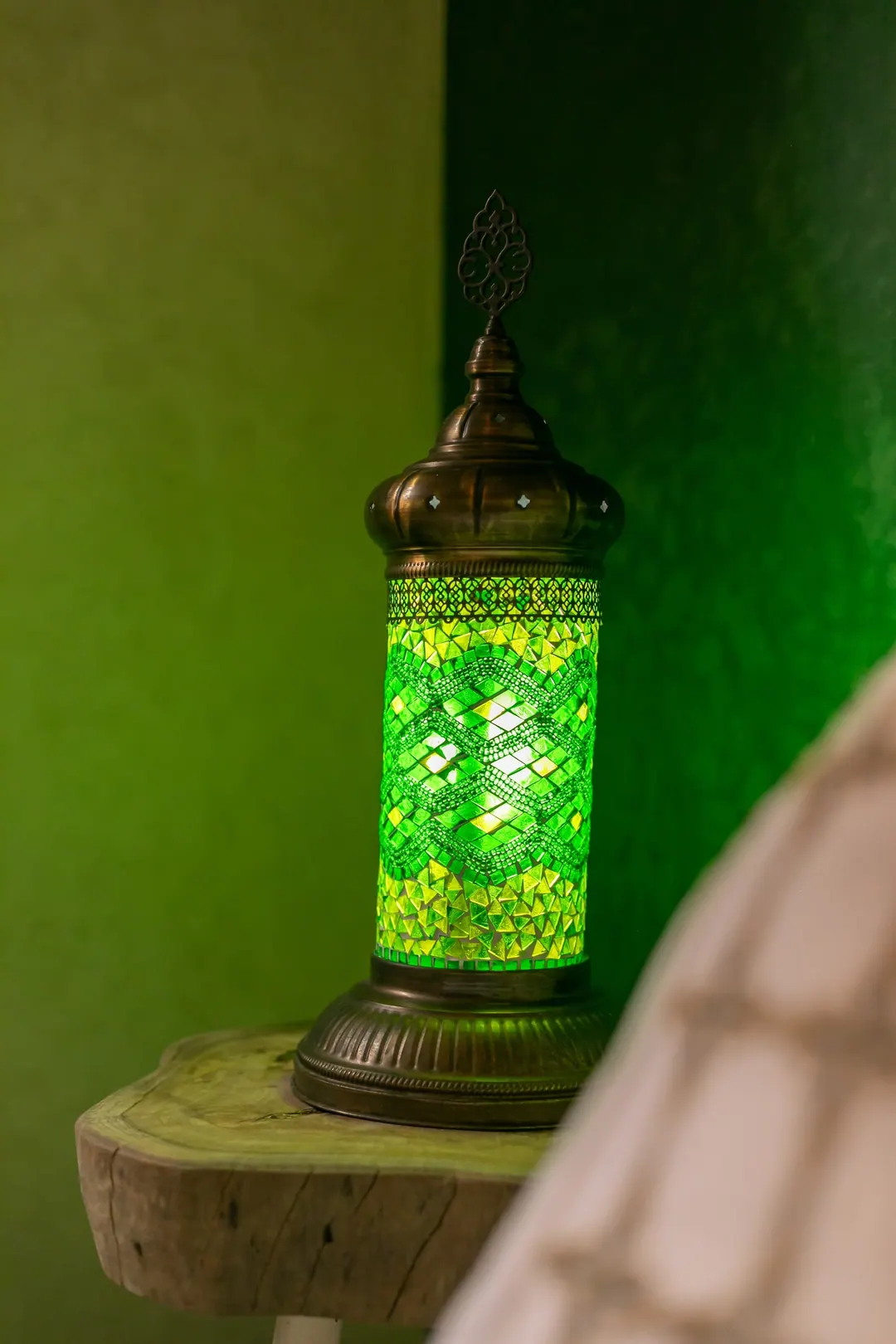Emerald room: carved headboard on an emerald tadelakt wall, green lantern and zellige floor
