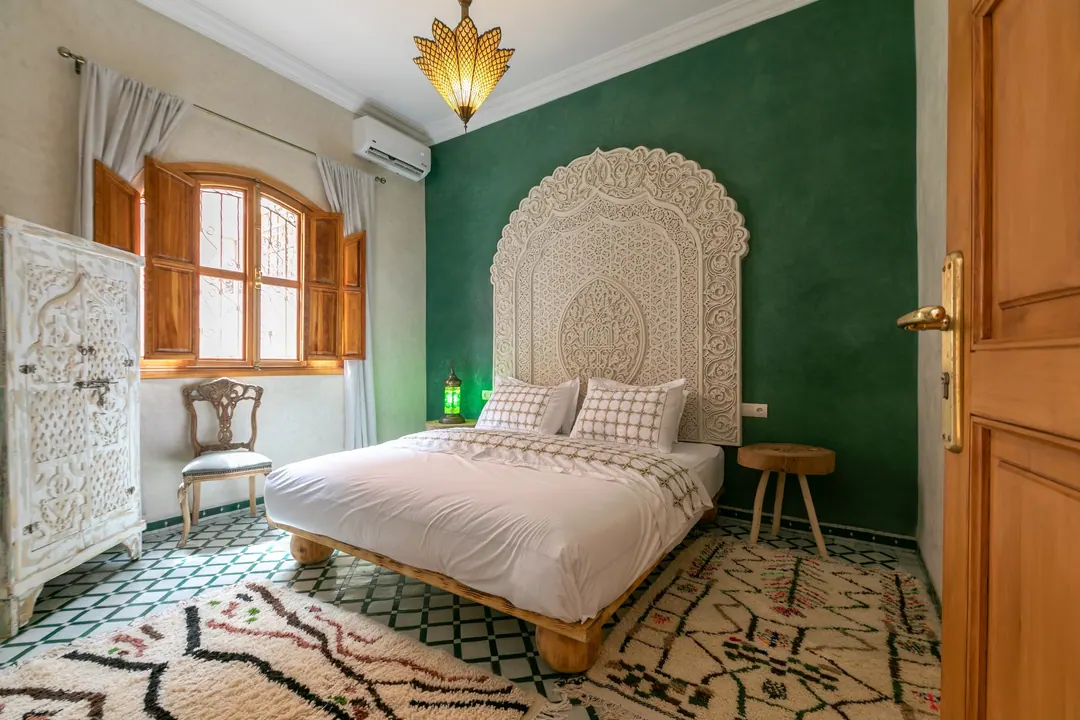 Emerald room: carved headboard on an emerald tadelakt wall, green lantern and zellige floor