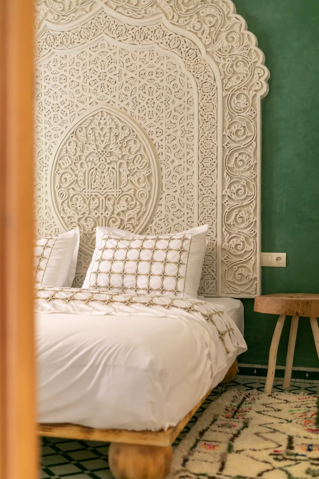 Emerald room: carved headboard on an emerald tadelakt wall, green lantern and zellige floor