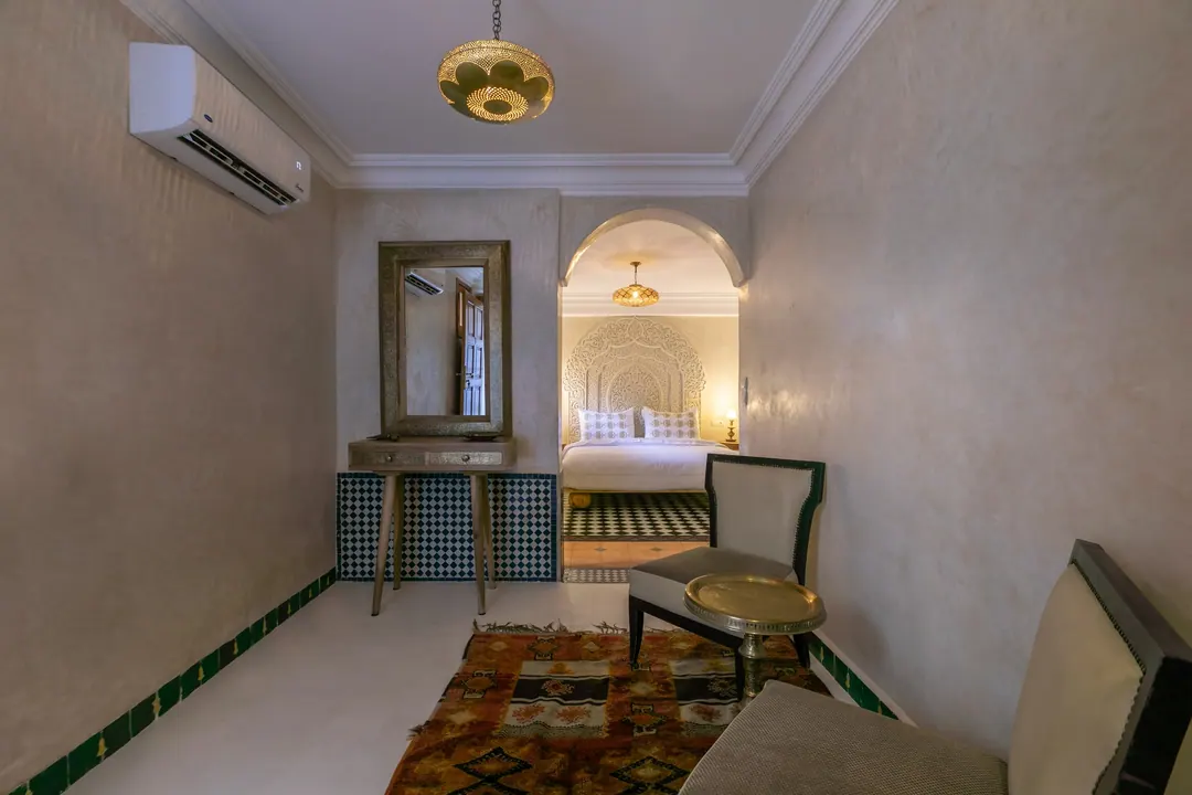 Ivory room: carved plaster headboard, bedside lamps and a black-and-white zellige floor