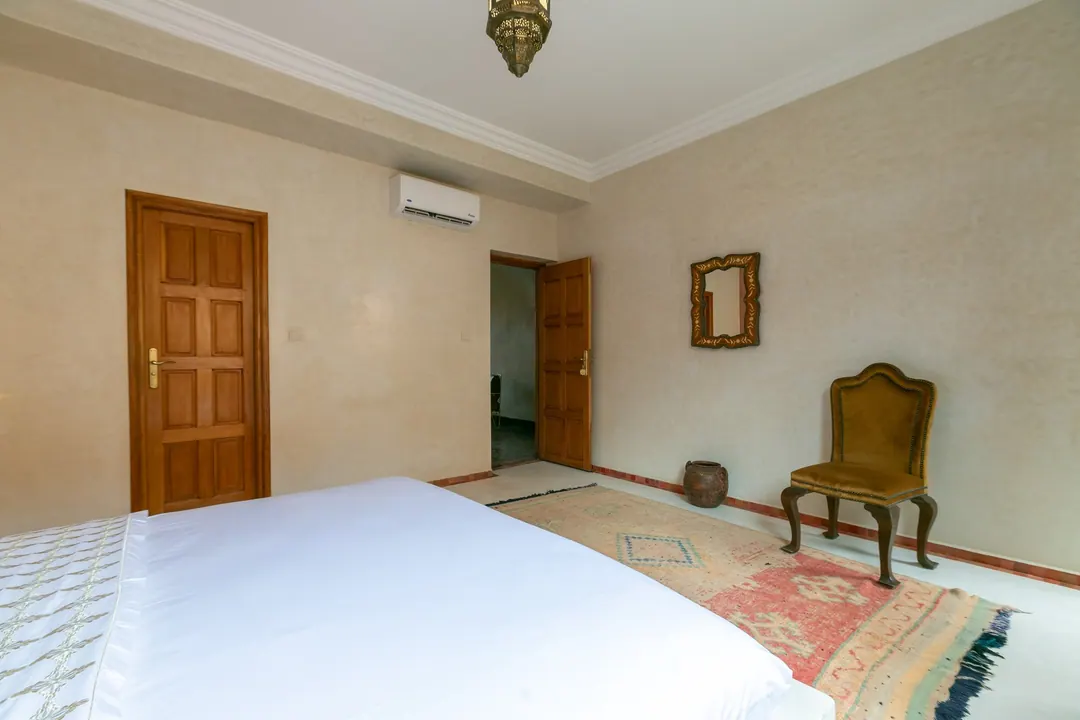 Terracotta room: carved white headboard on a rose-clay wall, cedar shutters and Berber rugs
