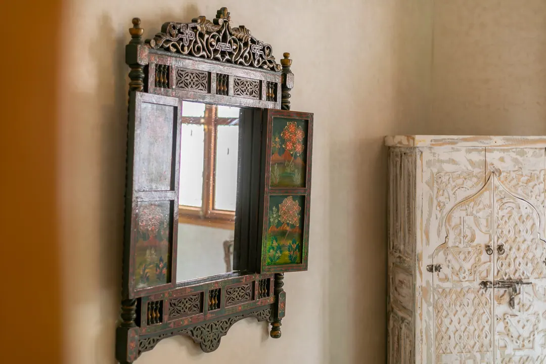Emerald room: carved headboard on an emerald tadelakt wall, green lantern and zellige floor