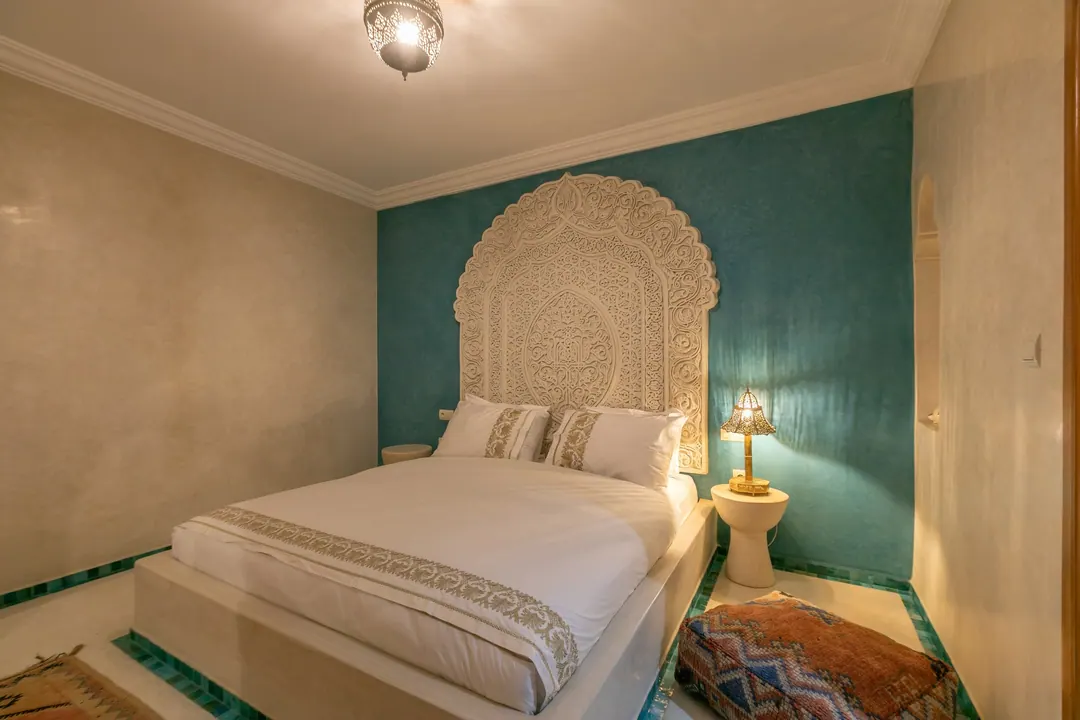 Turquoise room: carved plaster headboard against a deep turquoise wall, leather lounge chair
