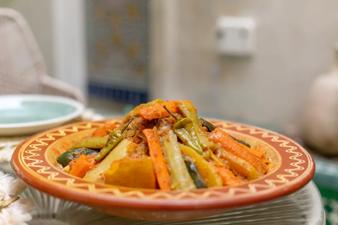 Seven-vegetable couscous in a terracotta dish with celadon plates