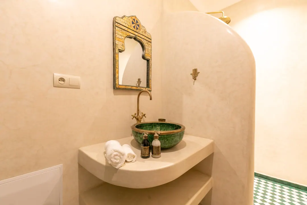 Emerald room bathroom with a hand-glazed green basin and brass fittings