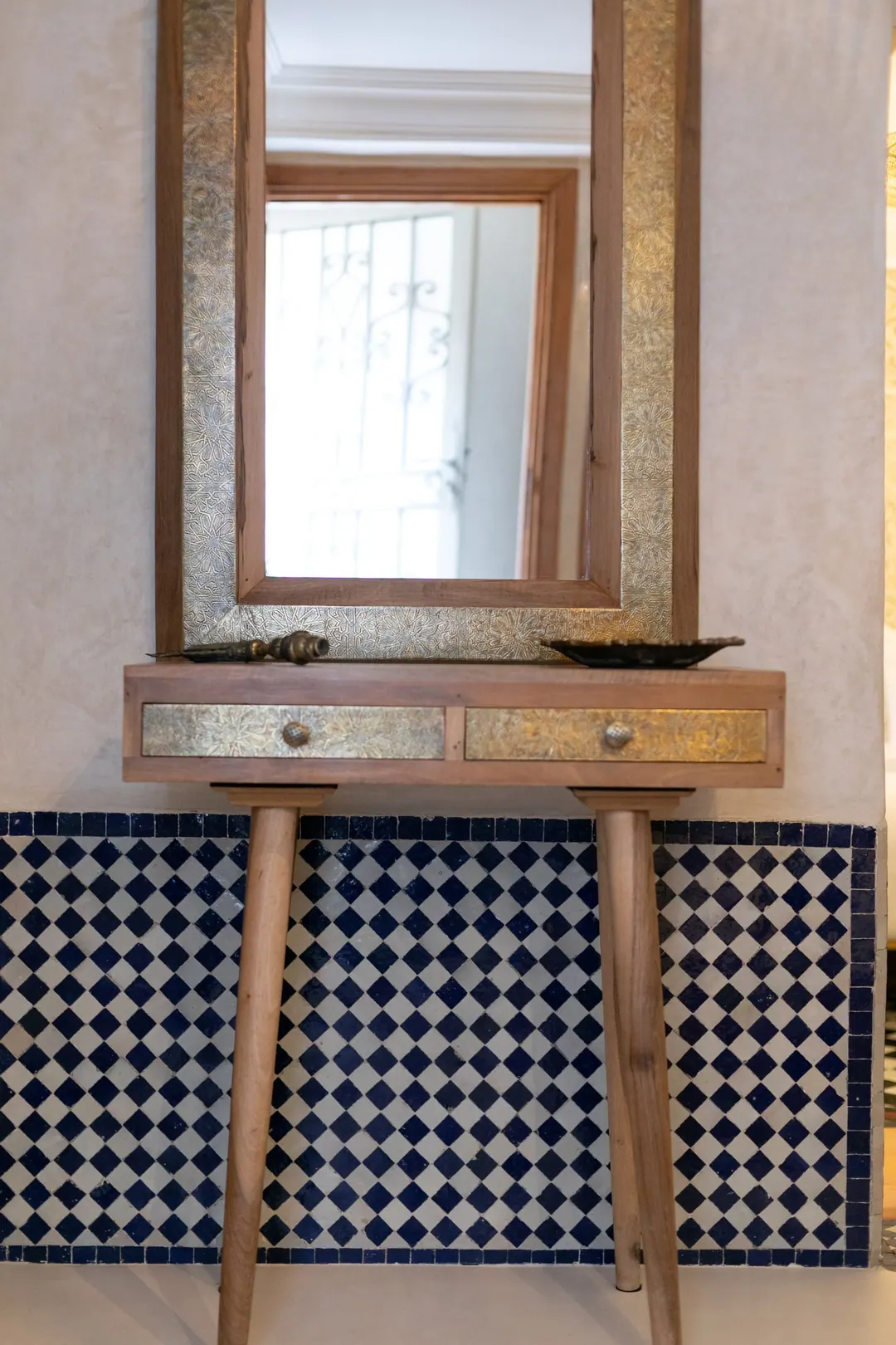 Ivory room: carved plaster headboard, bedside lamps and a black-and-white zellige floor