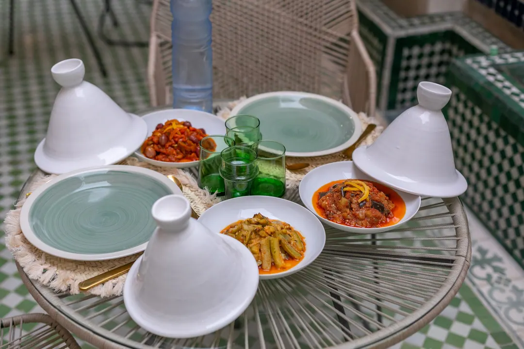 Lunch of seasonal tagines served under white ceramic lids on the patio